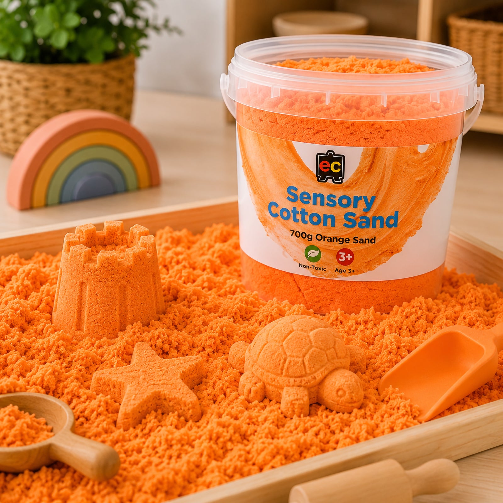 Orange sensory cotton sand displayed in a wooden sensory tray with moulded castle, turtle, and star shapes for imaginative tactile play.