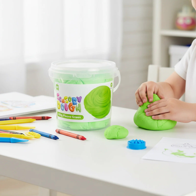 Child using Educational Colours Sensory Dough 250g Fluoro Green at a table with crayons and creative play accessories during sensory learning activities.