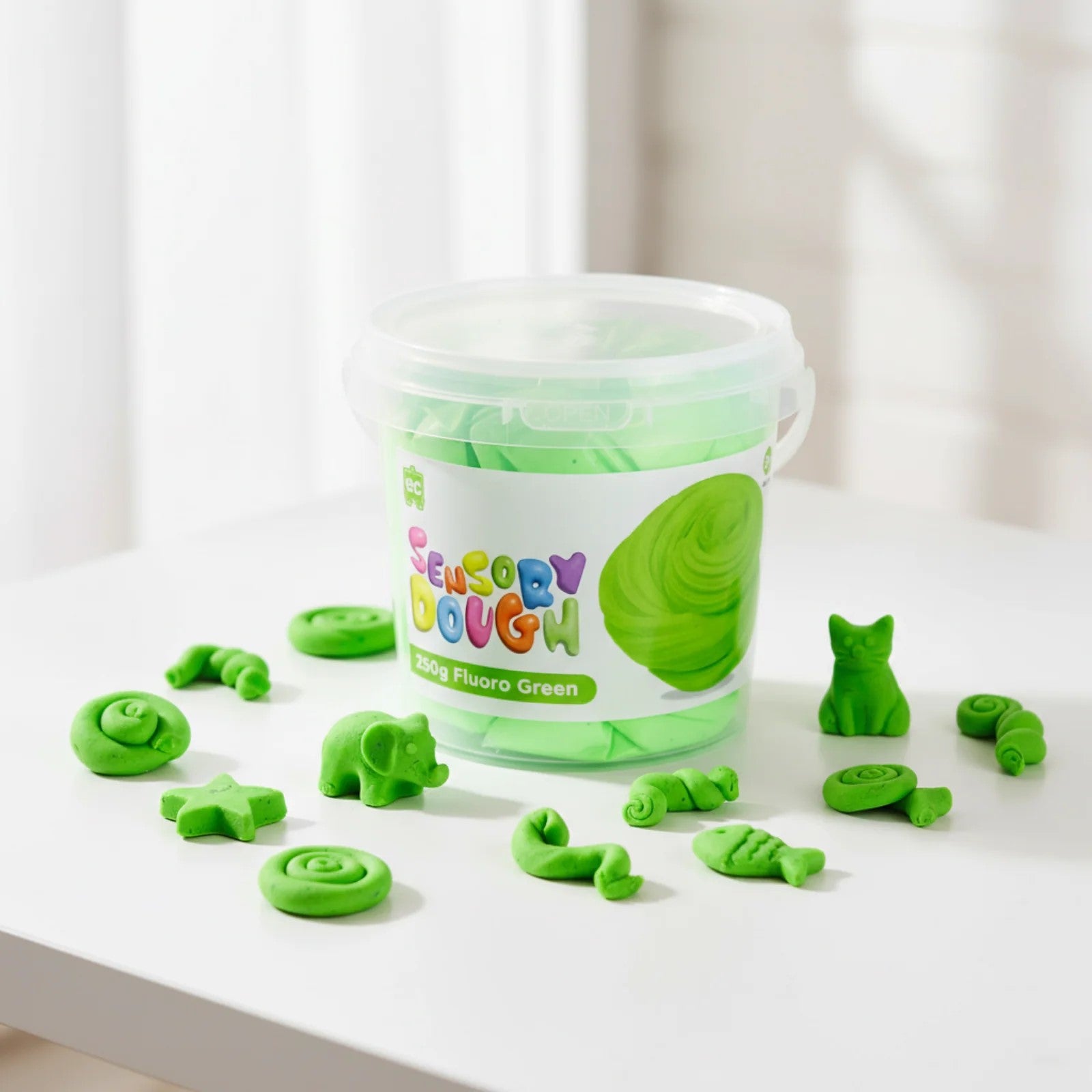 Fluoro green sensory dough displayed with small shaped creations including stars, animals, and spiral designs highlighting imaginative modelling possibilities.