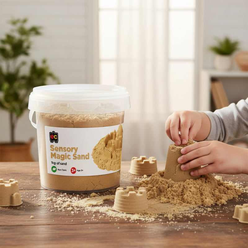 Child creating detailed sandcastle shapes using Educational Colours Sensory Magic Sand 1kg Natural on a wooden table beside the reusable storage tub in a bright indoor learning space.