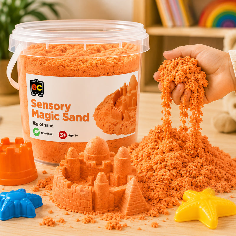Close up of orange Educational Colours Sensory Magic Sand flowing through a child’s hand beside detailed sand castle models and colourful moulds.