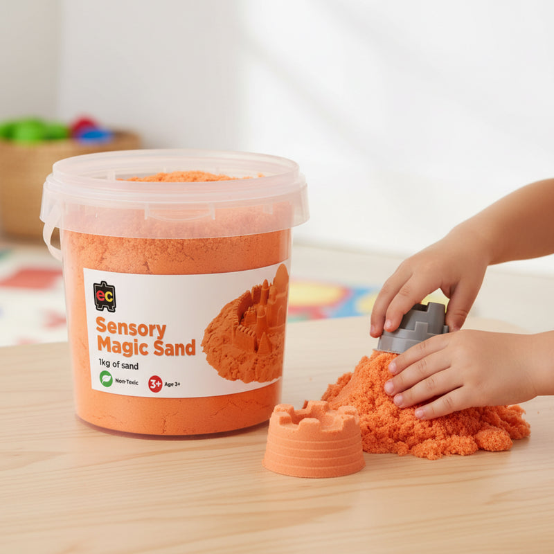 Young child using moulds with bright orange sensory magic sand during imaginative tactile play activity with reusable 1kg container nearby.