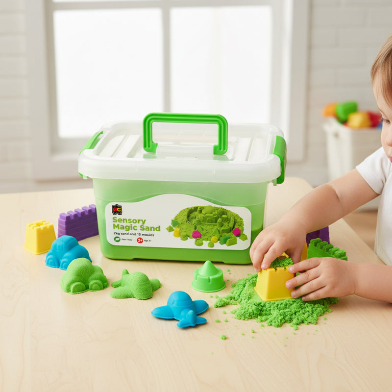 Young child pressing yellow mould into green sensory magic sand beside reusable storage tub and assorted colourful mould accessories.