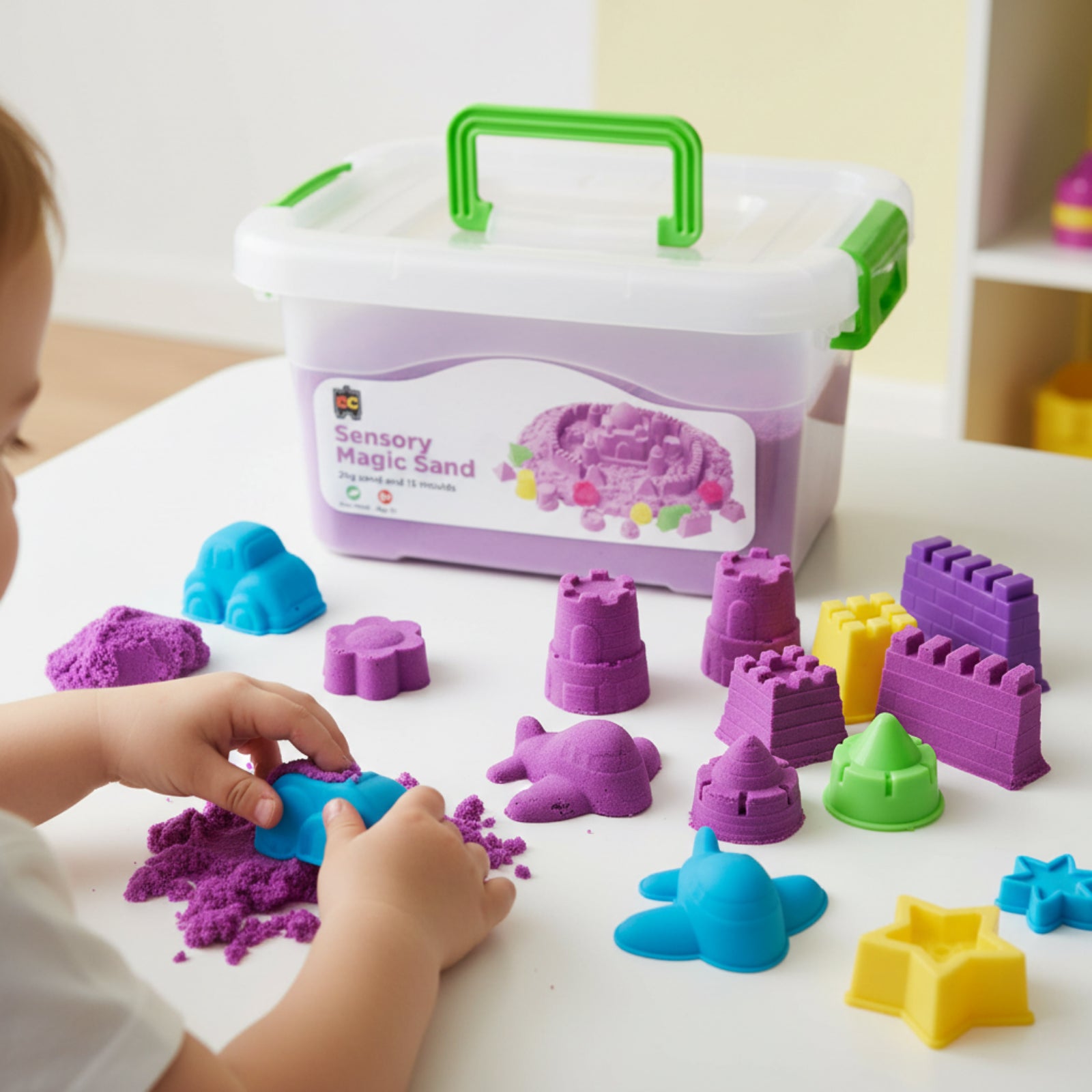 Young child using blue mould with purple sensory magic sand surrounded by castle moulds, bright accessories, and reusable Educational Colours storage container.