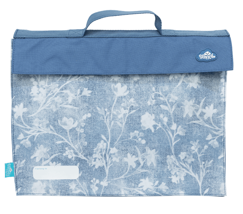 Front of the Spencil Denim Daze library bag showing faded blue denim texture with pale botanical sprigs and a mid-blue flap, with the top carry handle, fold-over flap and white name pocket at the lower left