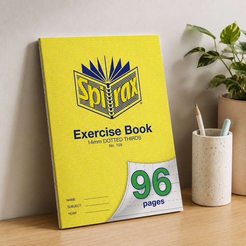 Spirax 109 A4 Exercise Book standing upright against a neutral wall on a wooden desk with stationery holder and indoor plant, creating a modern classroom or home office lifestyle setting.