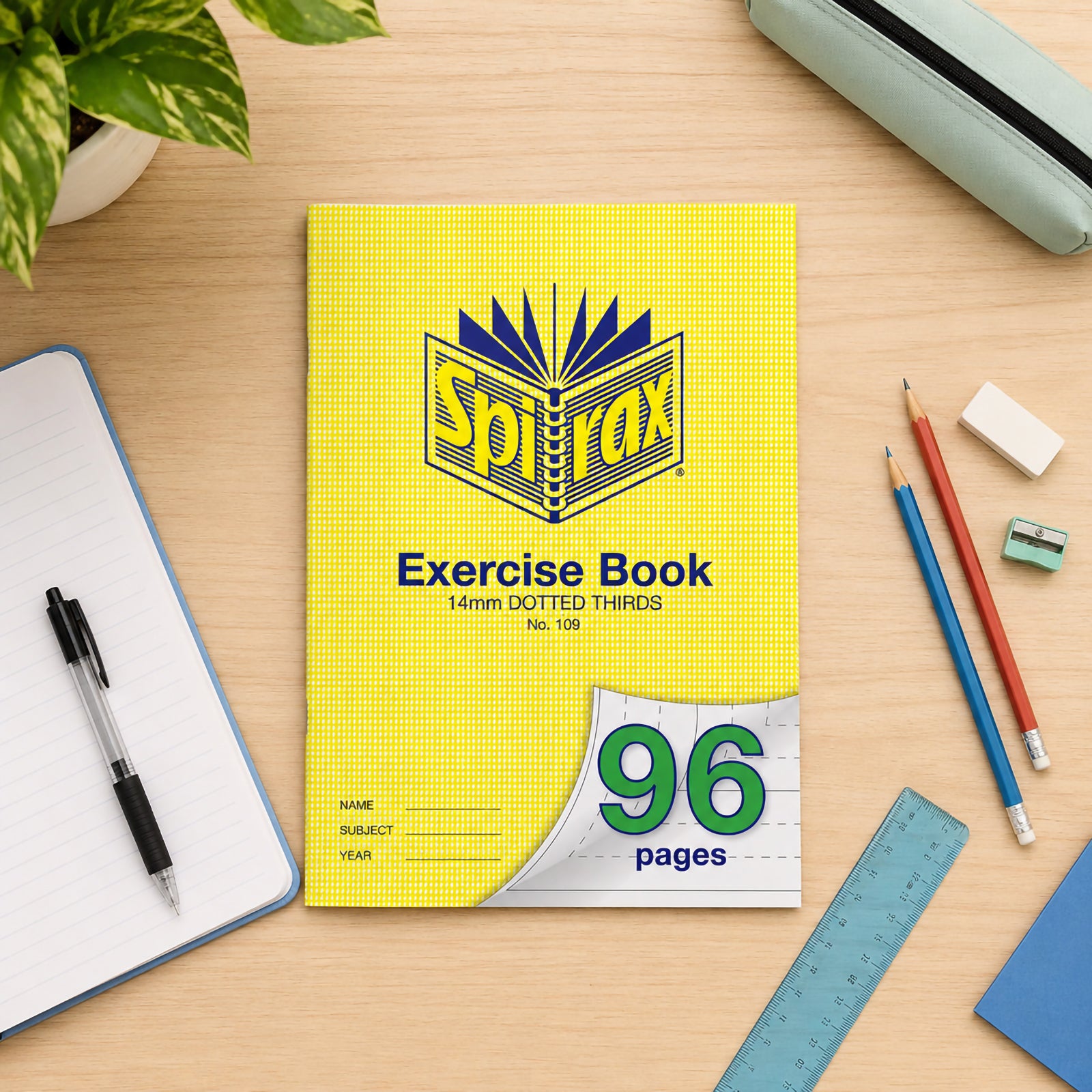 Top view of the Spirax 109 A4 96 page exercise book surrounded by stationery including pencils, ruler, notebook, eraser and pencil case on a clean wooden desk, demonstrating an organised school workspace.