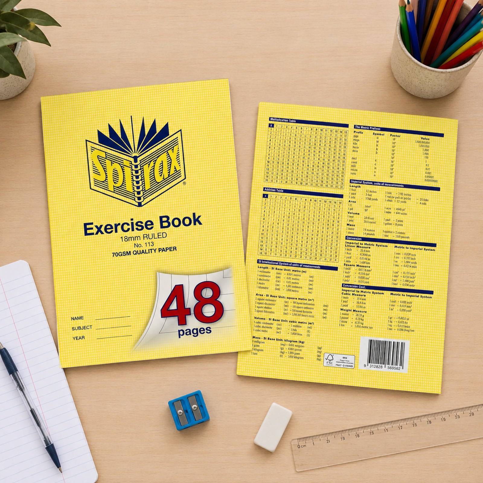 Front and back views of the Spirax 113 A4 48 page exercise book displayed on a school desk with pencils, ruler, notebook, eraser and sharpener, highlighting cover details and reference tables.