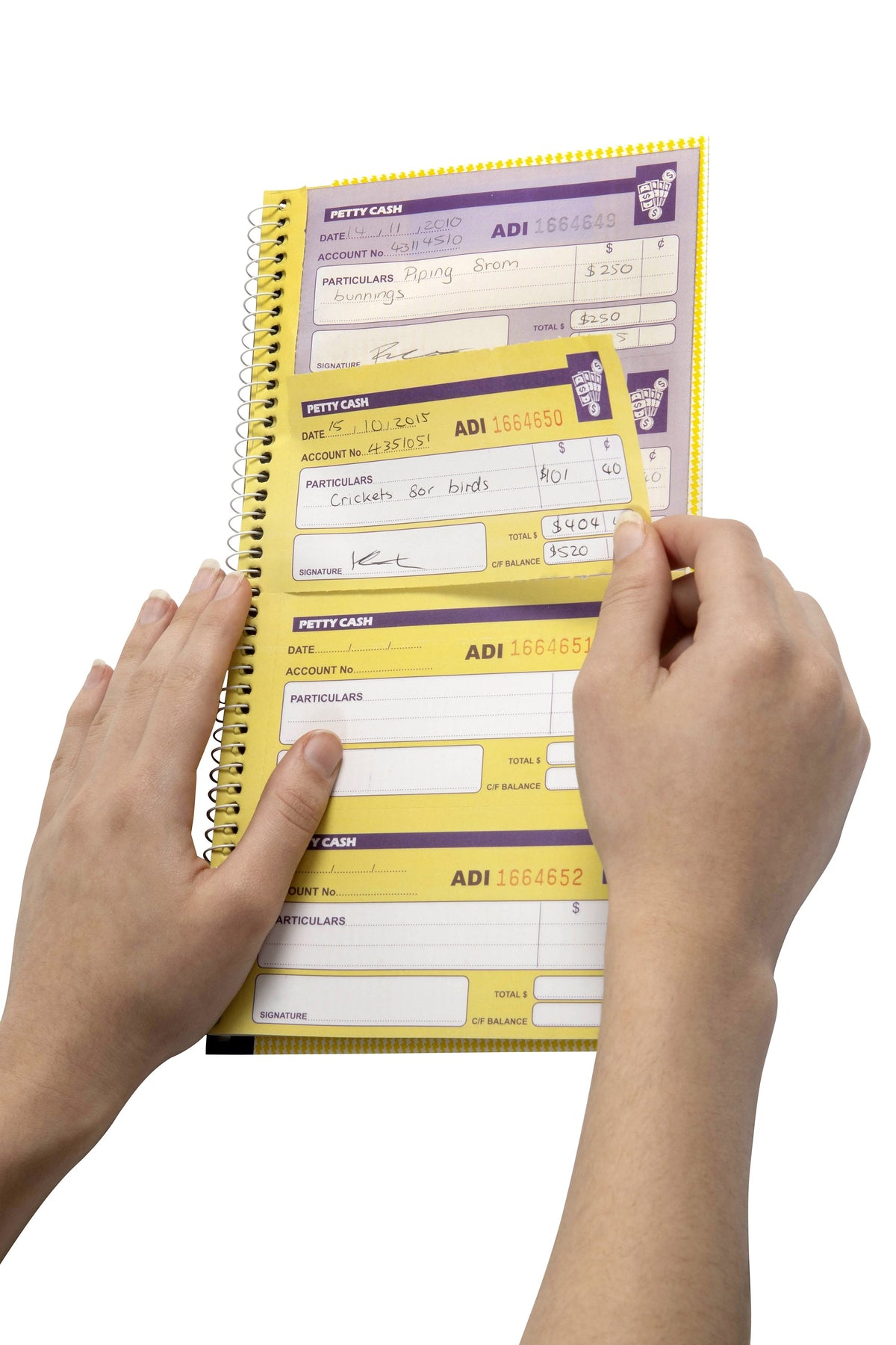 Hands tearing a completed petty cash voucher out of a Spirax No. 552 petty cash book, with the written duplicate showing through on the page beneath