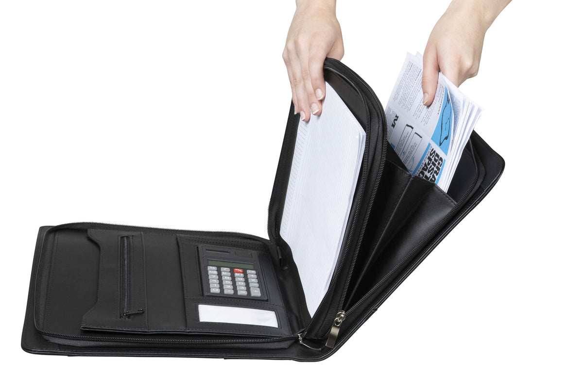 Hands lifting papers out of the expanding compartments of the open Spirax executive compendium, with the calculator visible on the left flap