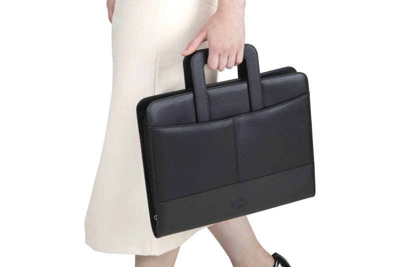 Spirax executive compendium carried by one of its handles, closed and zipped, held at the side of a person in a cream skirt