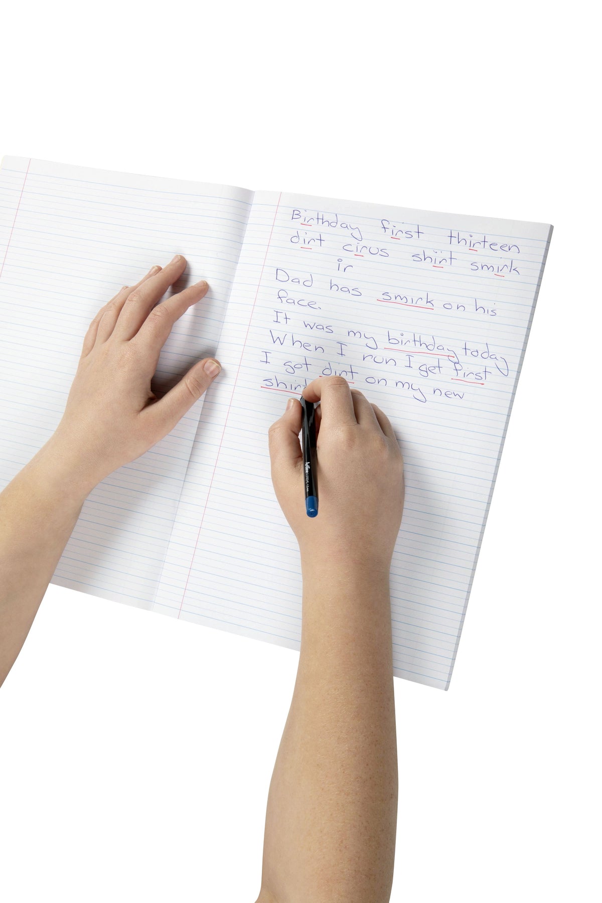 Hands writing spelling words in blue pen on the 14mm dotted thirds pages of an open Spirax 103 exercise book, with some words underlined in red