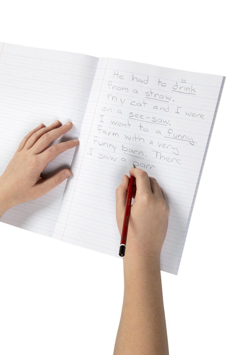 Child writing sentences in pencil on the 18mm dotted thirds lines of an open Spirax 117 A4 exercise book, one hand resting on the left page