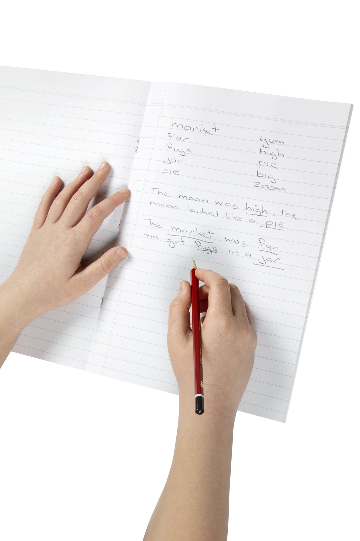 Child writing words and sentences in pencil on the blue ruled lines of an open Spirax 211 A4 exercise book