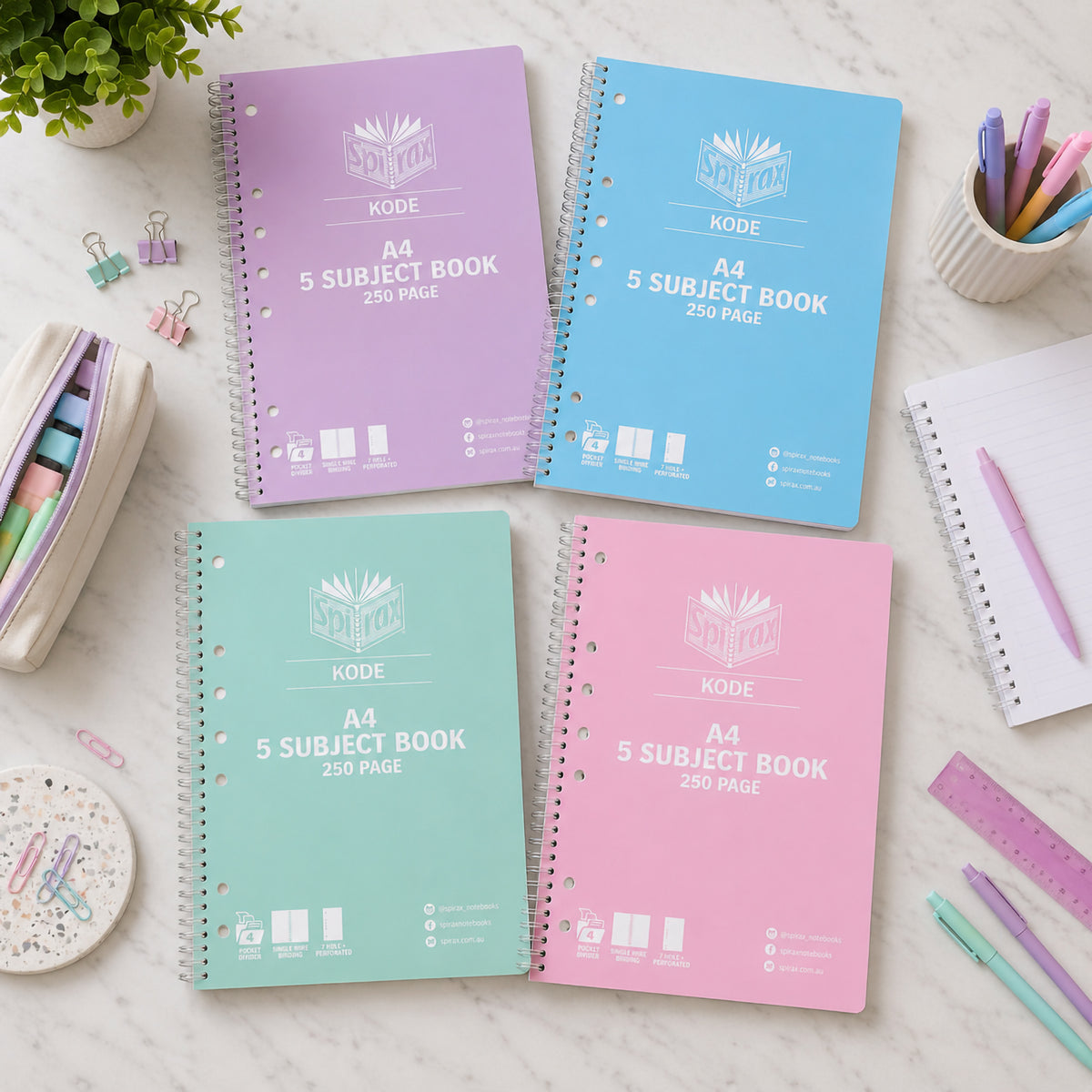 Flat lay of four Spirax Kode 5 subject books in purple, light blue, mint green and pink on marble with pastel pencils and a ruler