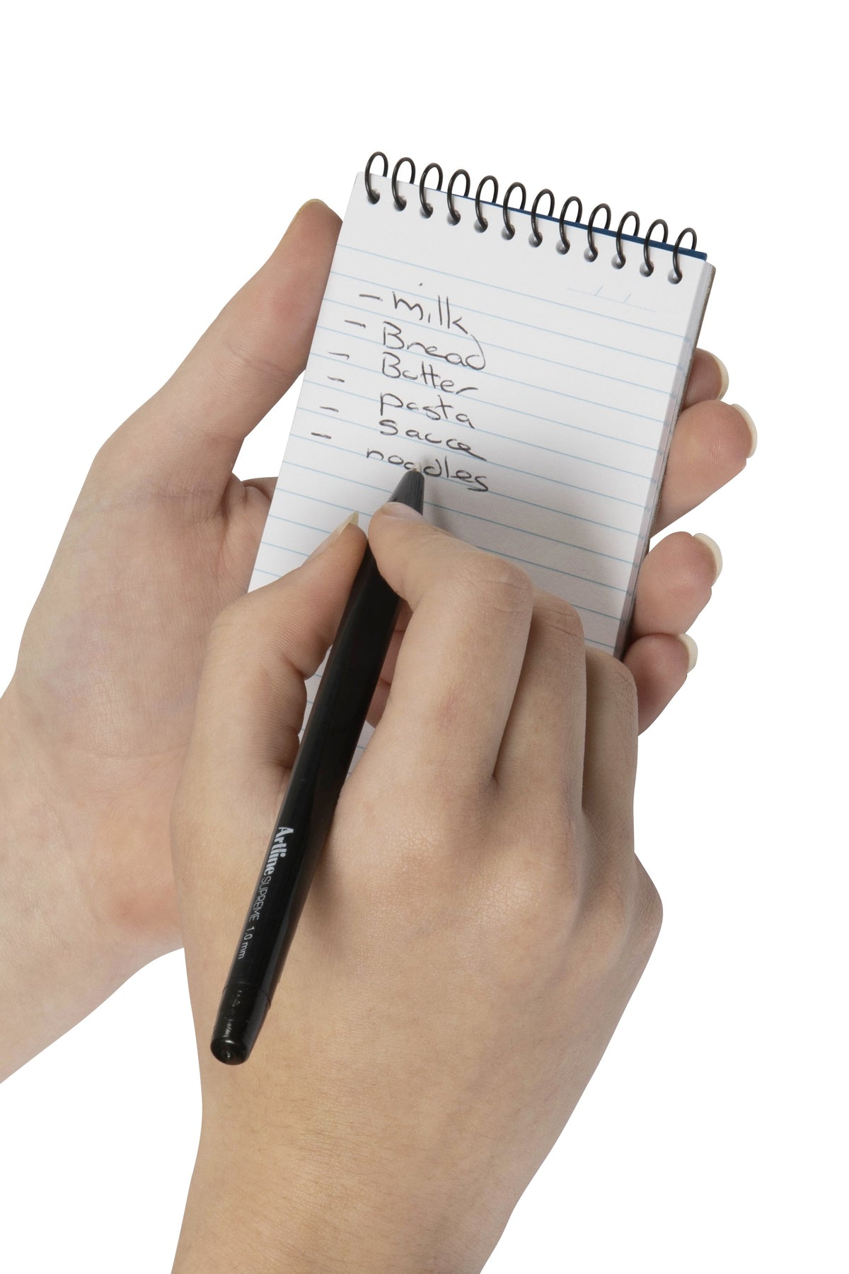 Hand holding a Spirax Kode P955 pocket notebook and writing a short shopping list on the ruled top opening page