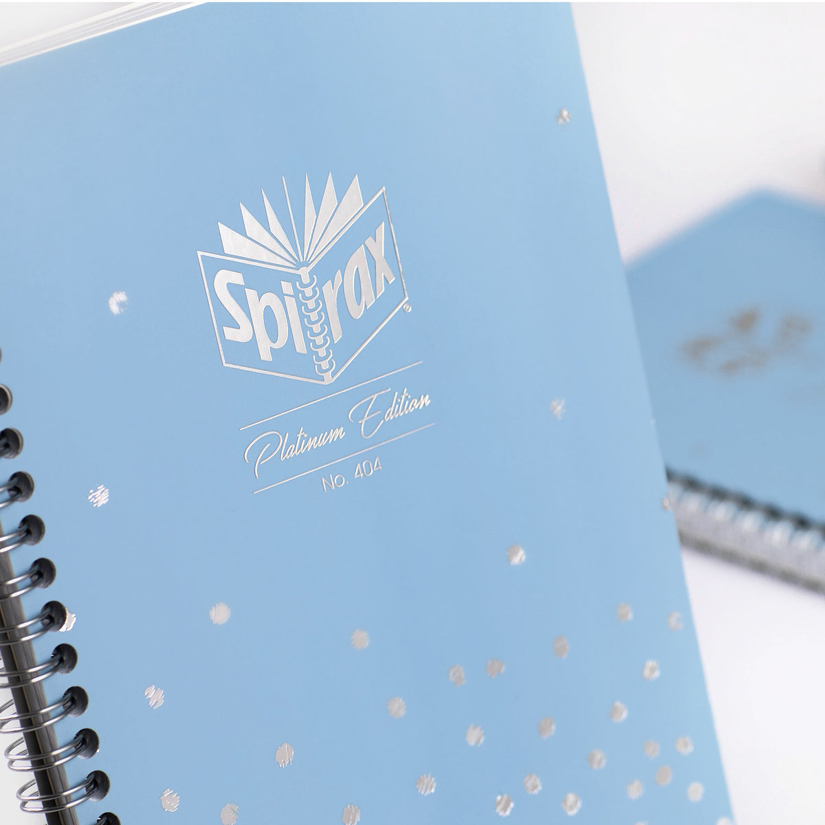 Close view of a blue Spirax Platinum Edition No. 404 A5 notebook cover with a silver Spirax logo and scattered silver dots, spiral binding in the foreground