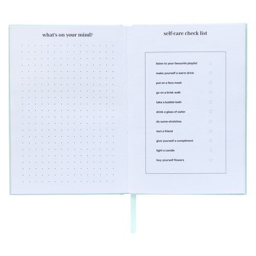 Spirax wellness journal open at a dotted page headed what is on your mind beside a printed self care check list