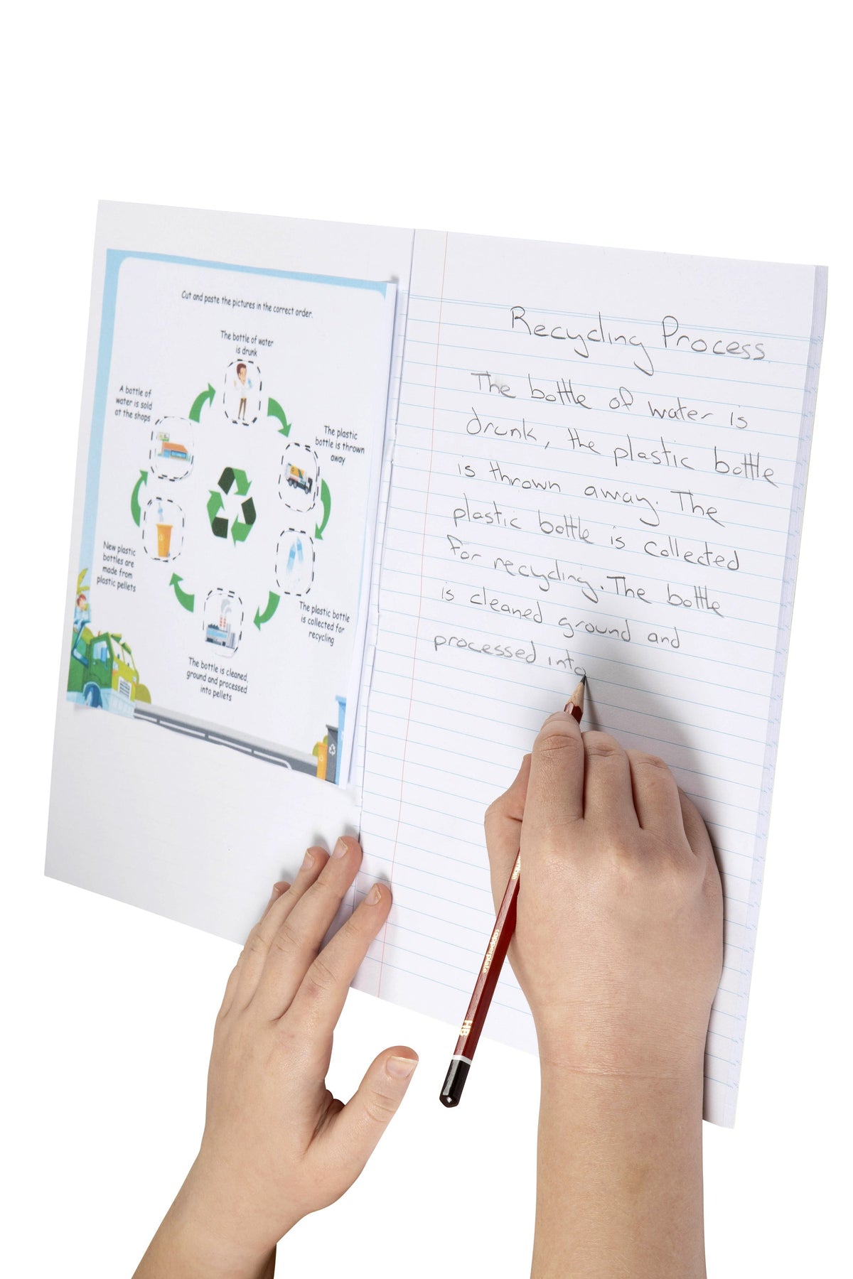 Child writing notes in pencil on the ruled page of a Spirax 144 project book, with a printed diagram glued onto the blank page opposite