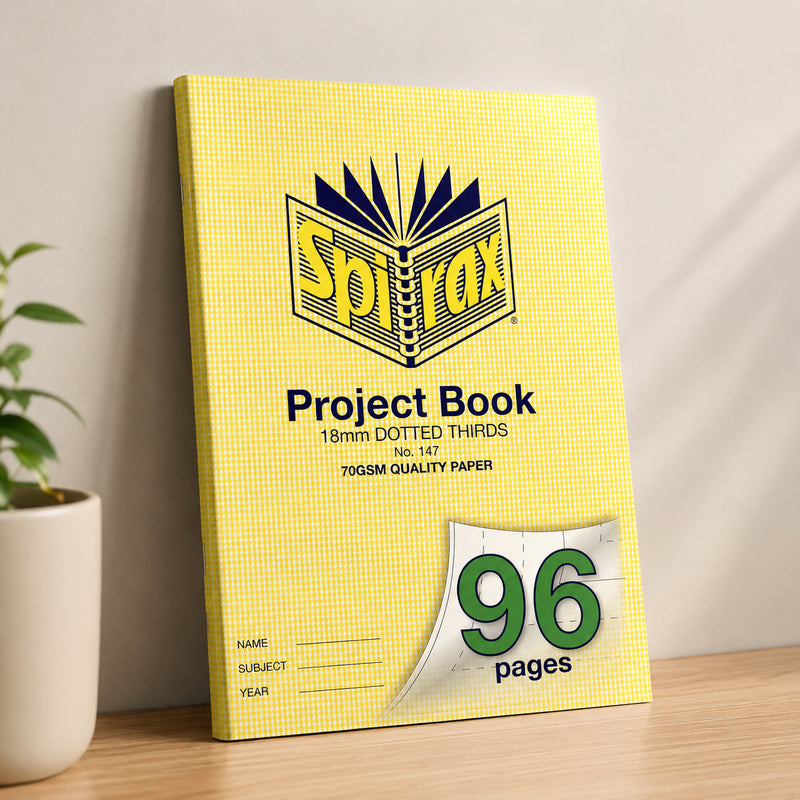 Spirax 147 project book leaning upright against a neutral wall on a wooden desk next to a potted plant