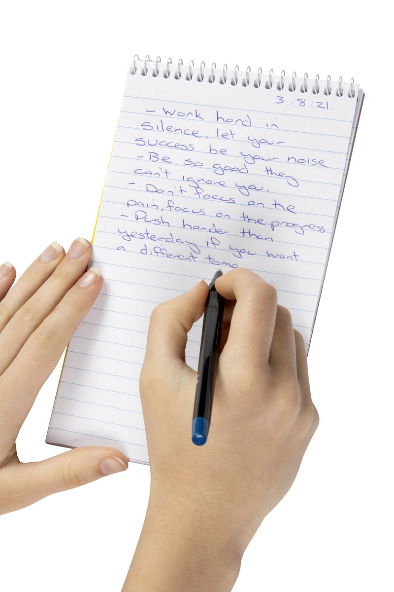 Hand writing notes in blue pen on the ruled page of a Spirax No. 563 top opening reporter note pad, held steady with the other hand