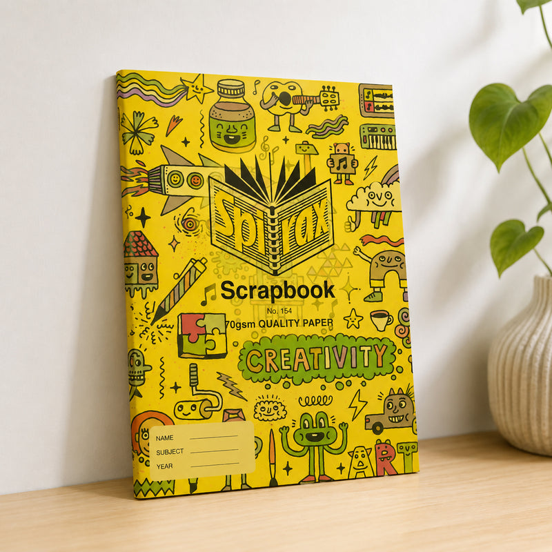 Spirax 154 scrapbook with its doodle print cover standing upright on a wooden desk beside a vase and a green plant