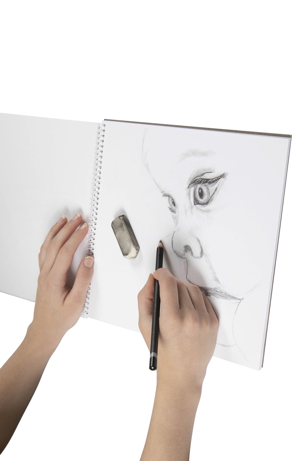 Hand drawing a pencil portrait of a face on a blank page of an open Spirax 578A sketch book folded back on its spiral, with an eraser resting on the page