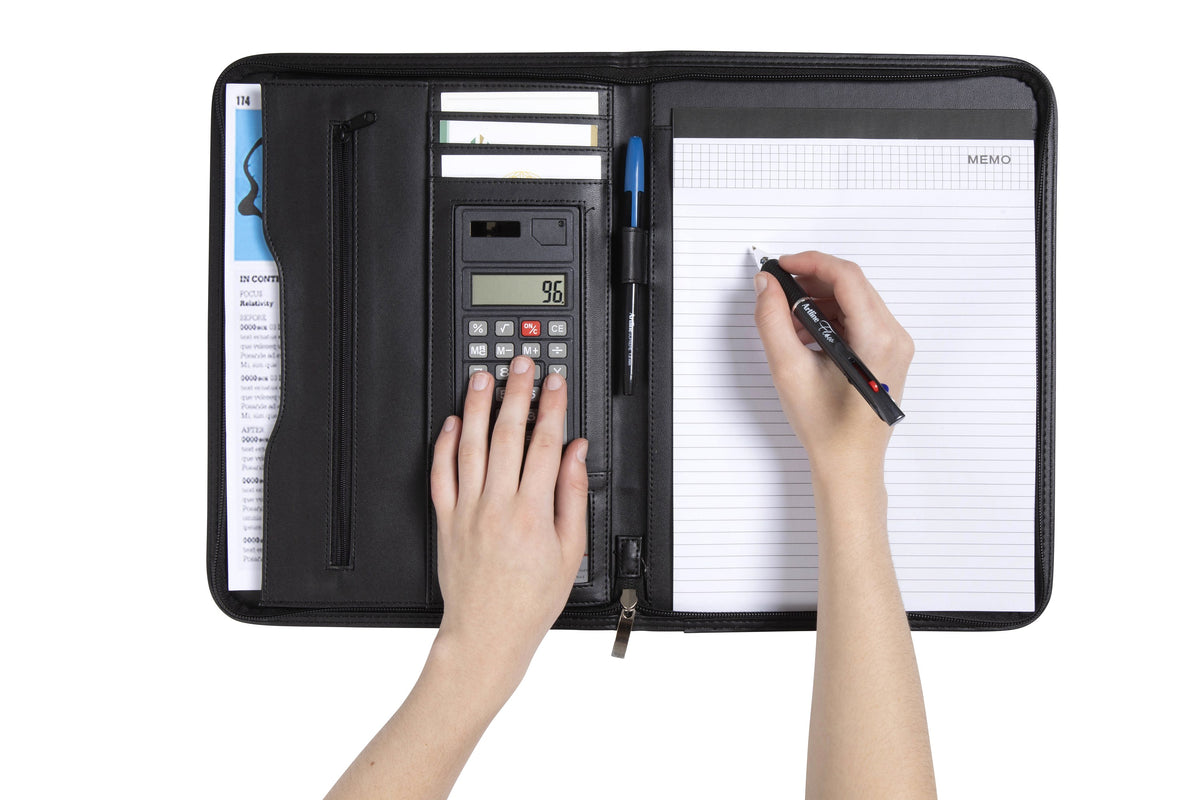 Open Spirax slimline compendium in use, one hand on the calculator keys and the other writing on the ruled memo pad in the right sleeve