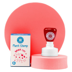 Retail packaging and Spot On Merit Stamp displayed on a presentation stand with soft pink background elements. The colourful teacher reward stamp combines convenience, durability and positive reinforcement for everyday educational use