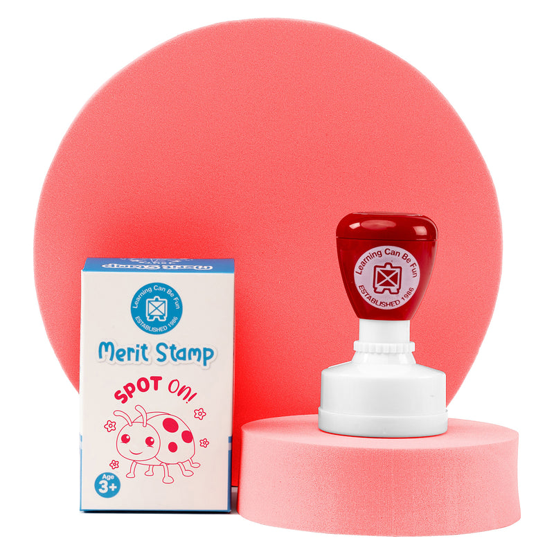 Retail packaging and Spot On Merit Stamp displayed on a presentation stand with soft pink background elements. The colourful teacher reward stamp combines convenience, durability and positive reinforcement for everyday educational use