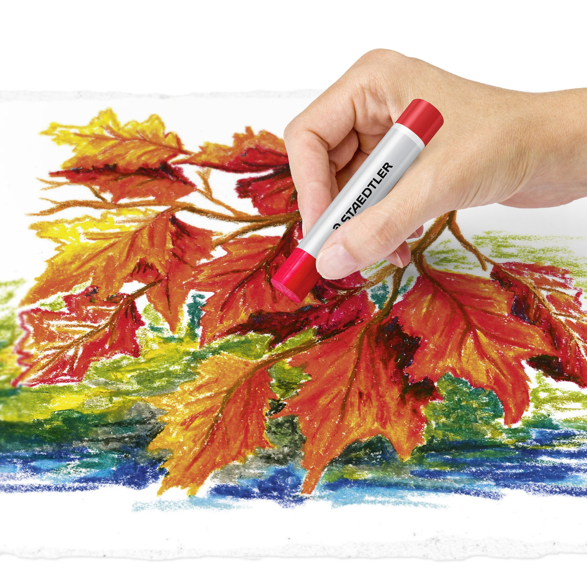 Artist hand working a red oil pastel over an autumn leaf picture in orange, red, yellow and blue