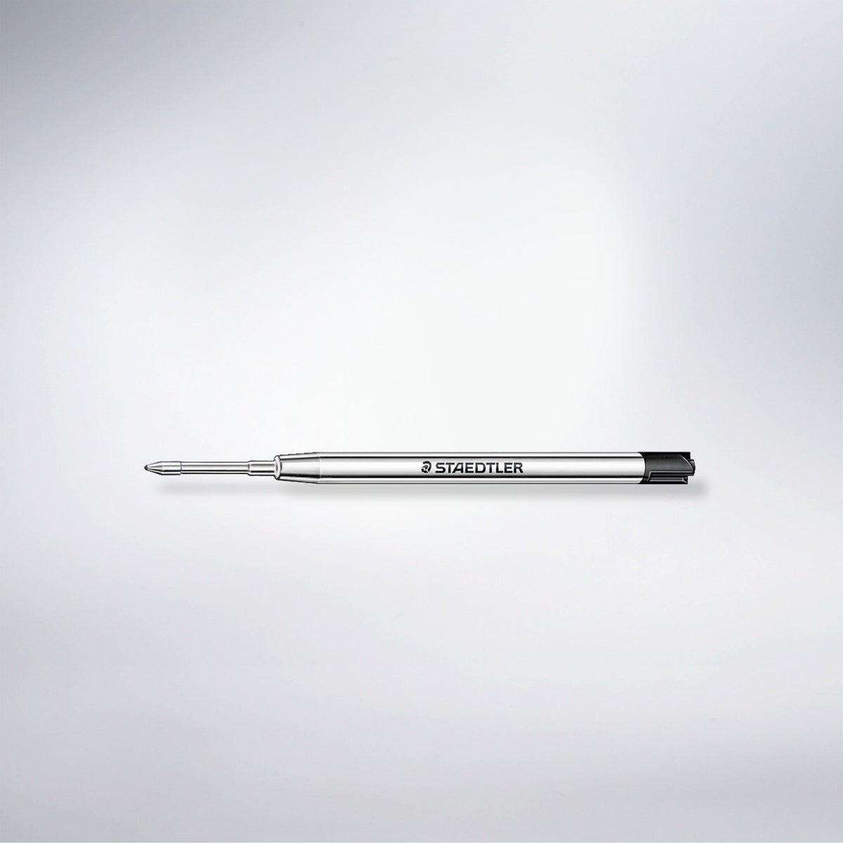 Single Staedtler 458 metal ballpoint refill with a black end, lying on a soft grey studio background