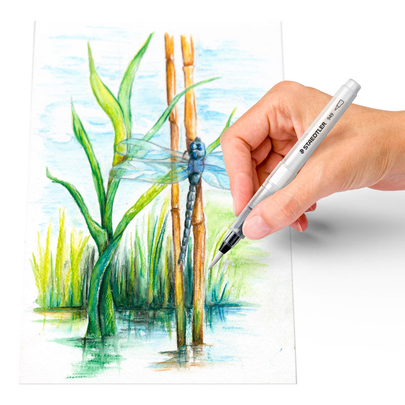 A hand using a Staedtler water brush to paint a watercolour of a dragonfly among green reeds