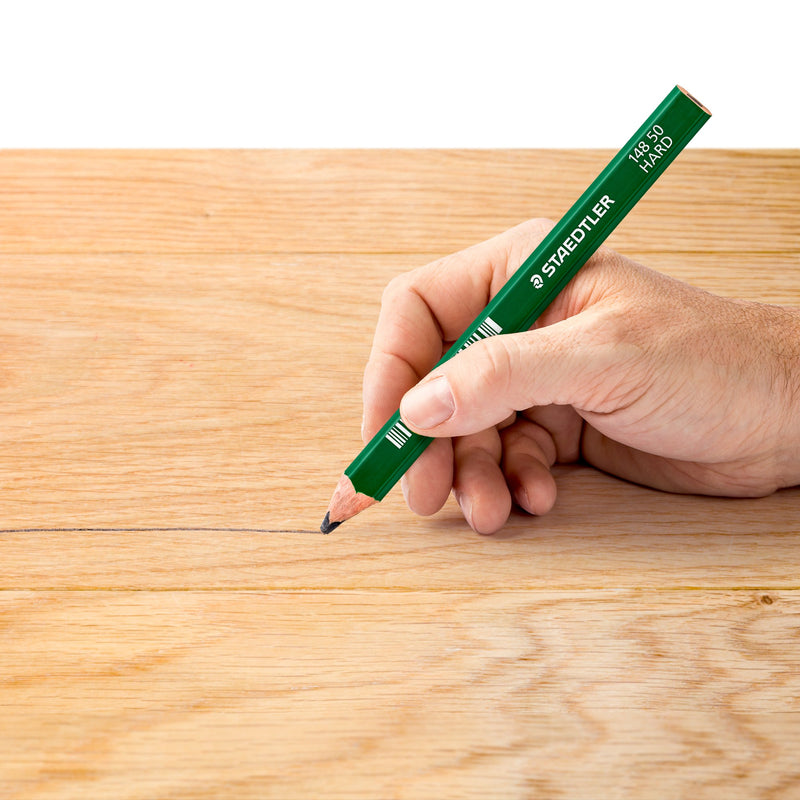 Hand drawing a line across a light timber board with a green Staedtler 148 50 carpenter pencil