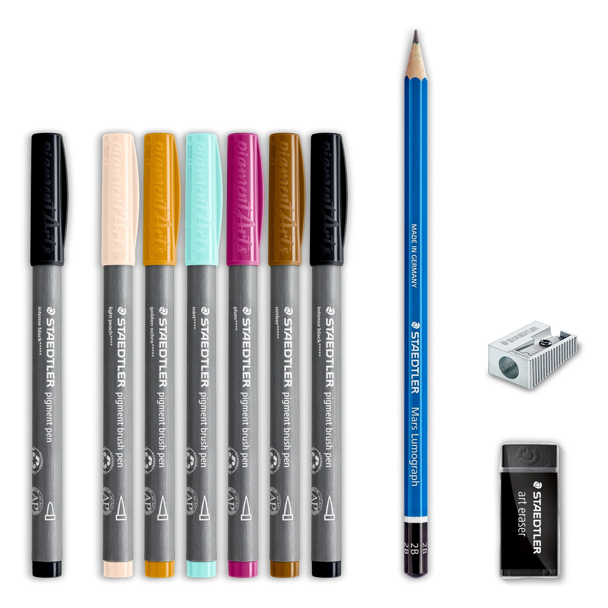 Contents of the set laid out: seven Staedtler pigment pens with black, cream, ochre, pale turquoise, magenta and brown caps, a blue drawing pencil, a metal sharpener and a black art eraser