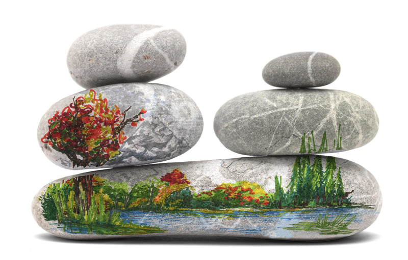 Smooth grey pebbles painted with an autumn tree, a lake and reeds, Staedtler example of decorating stones with permanent pens