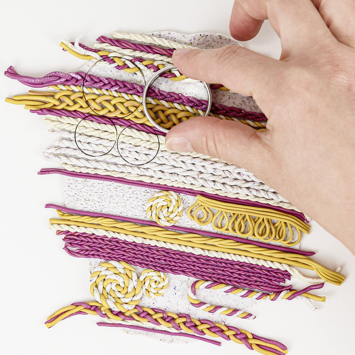 Rows of plaits, twists and spirals in berry, gold and speckled white clay forming a knit-look panel