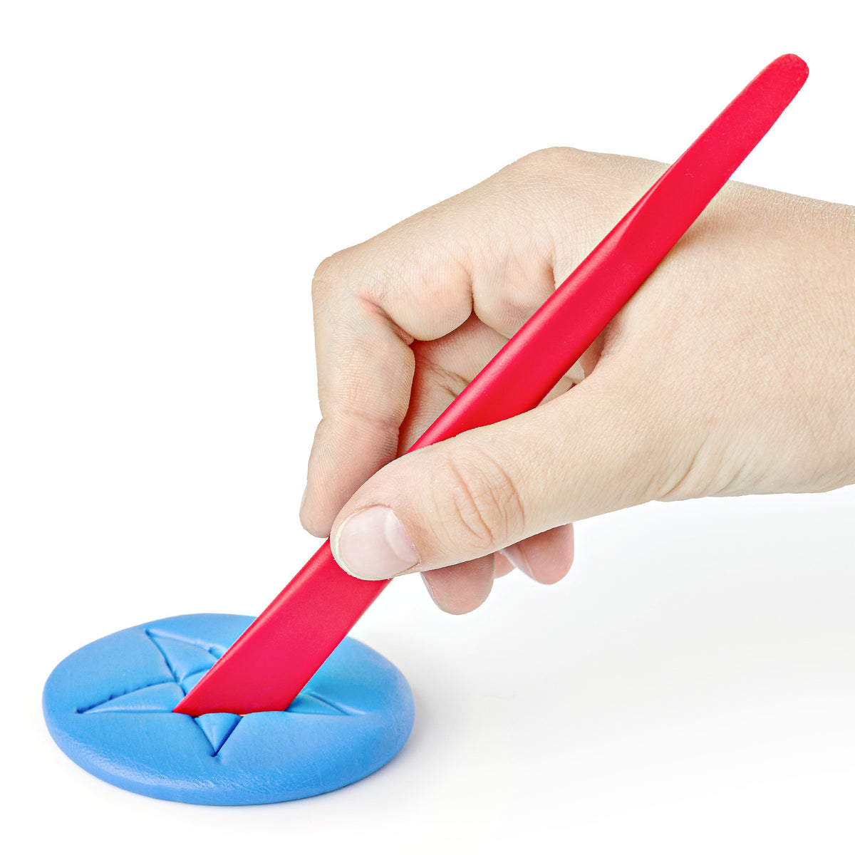 Hand pressing lines into a flattened disc of blue FIMO kids clay with a red modelling stick