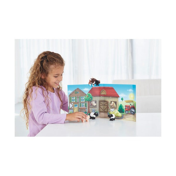 Girl playing with clay farm animals in front of the fold-out barn backdrop