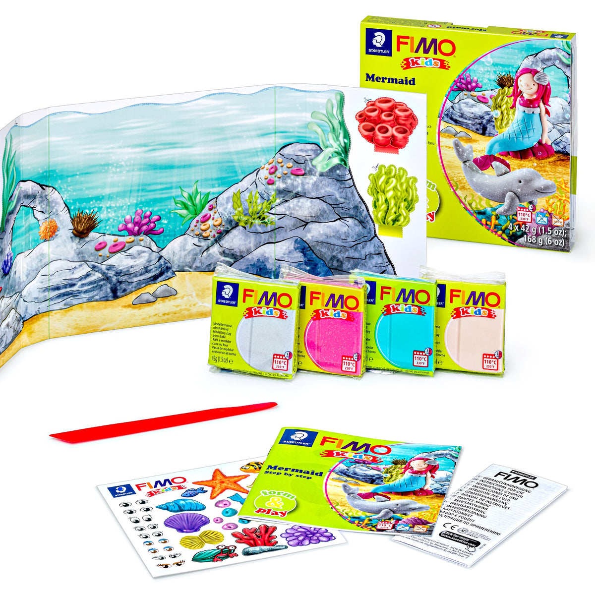 Mermaid set laid out: underwater rock backdrop, four clay blocks, red stick, instruction booklet and sticker sheet