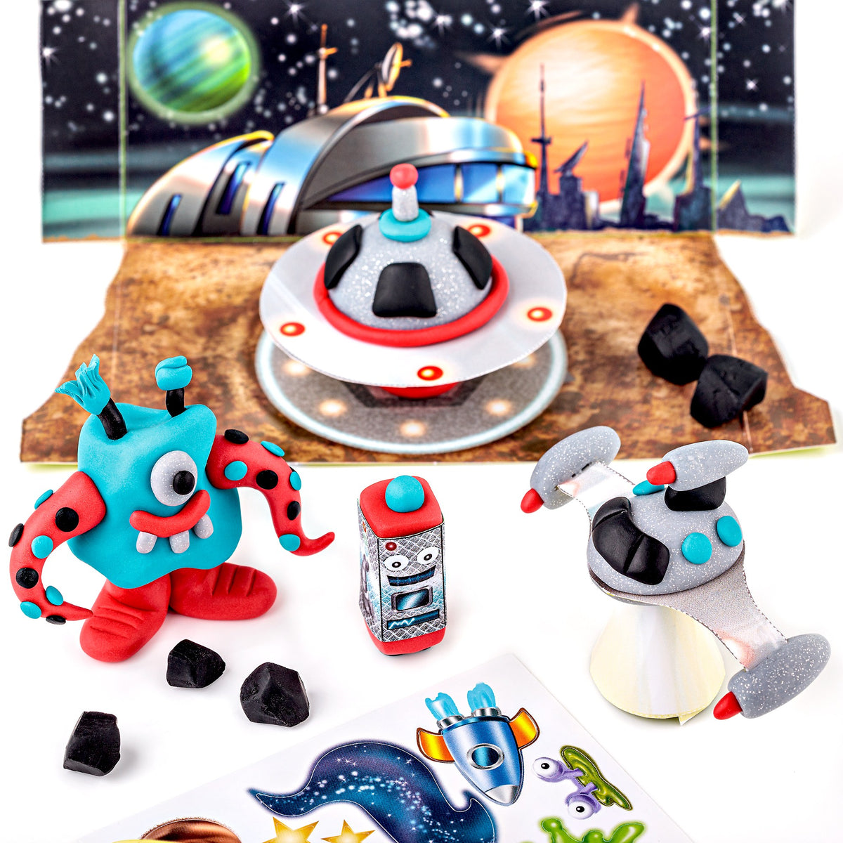 Finished Space set models: a turquoise and red one-eyed alien, a flying saucer and a silver robot on a planet surface in front of the backdrop