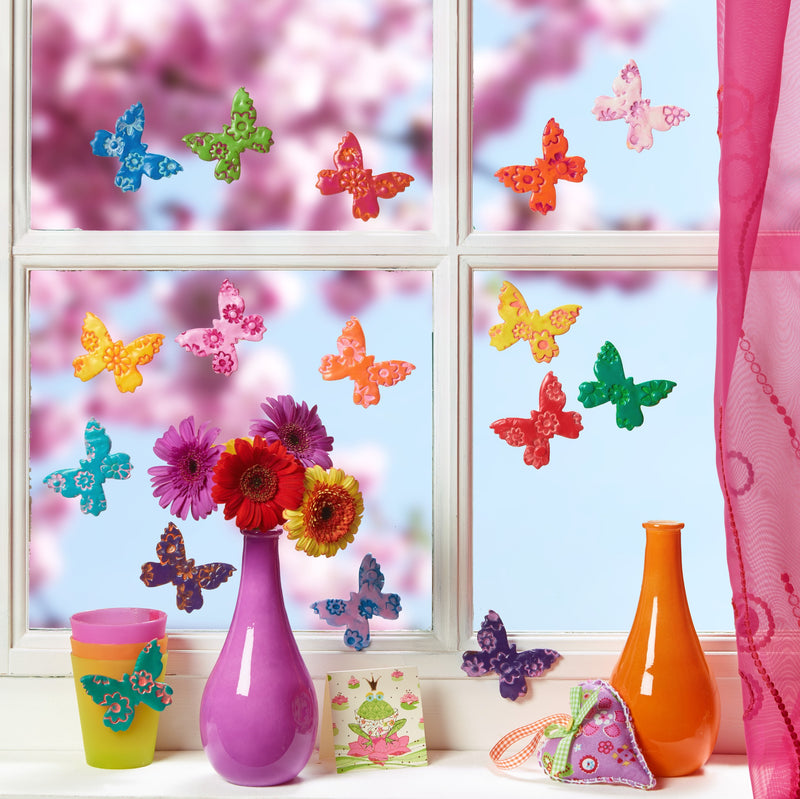 Staedtler photo of colourful FIMO kids butterflies stuck to a window above vases of flowers on a sunny sill