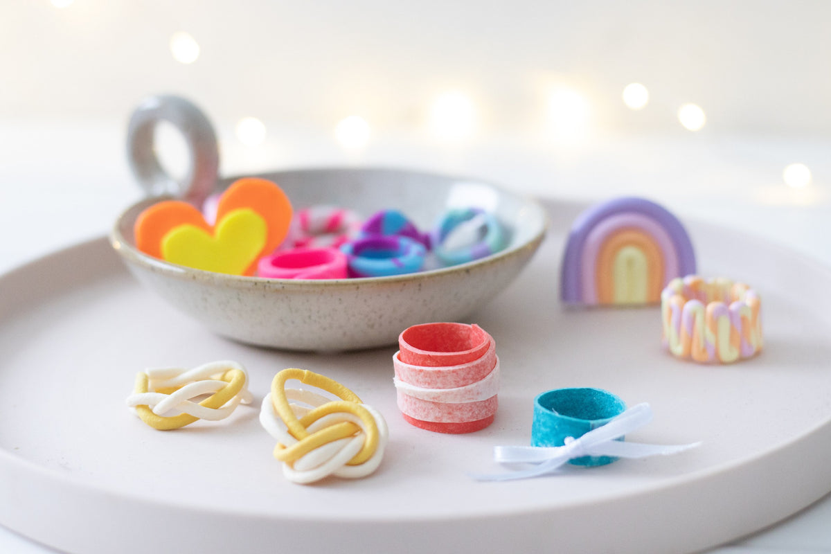 Staedtler photo of chunky FIMO leather-effect rings and knotted pieces in bright colours on a round white tray