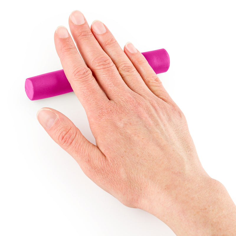 Pink FIMO soft being rolled into an even log under a flat hand, a demonstration of shaping the clay