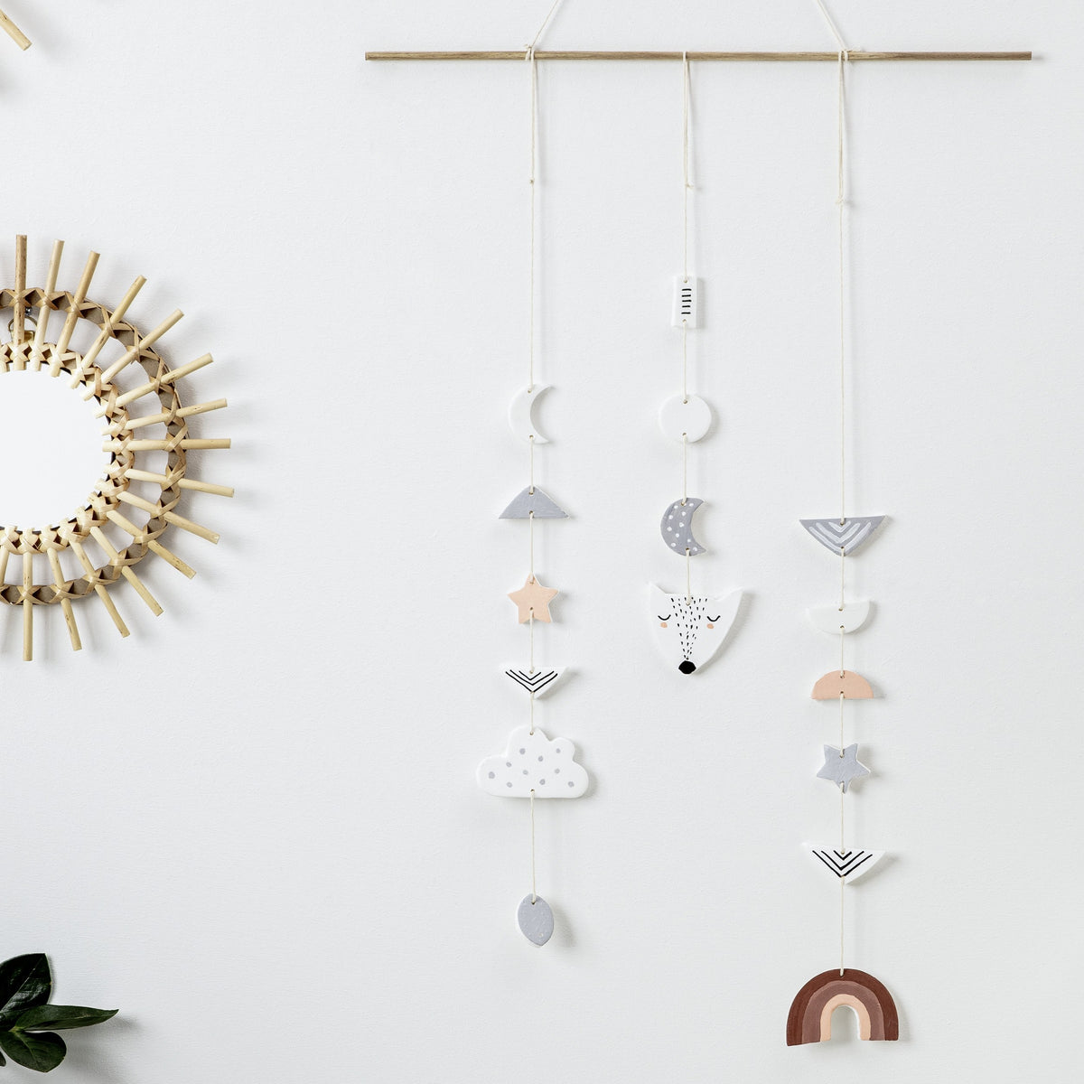 Decorative mobile of FIMOair light pieces on threads, white moons and stars, a grey cloud and a terracotta rainbow