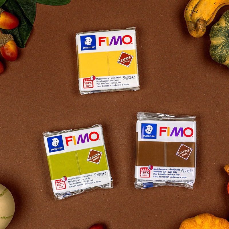 Three FIMO leather effect blocks, one olive green, one yellow and one brown, on a brown background with small gourds