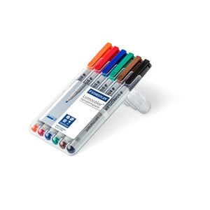 Open Staedtler Lumocolor 312 WP6 box propped up as a stand, holding orange, red, blue, green, brown and black broad pens
