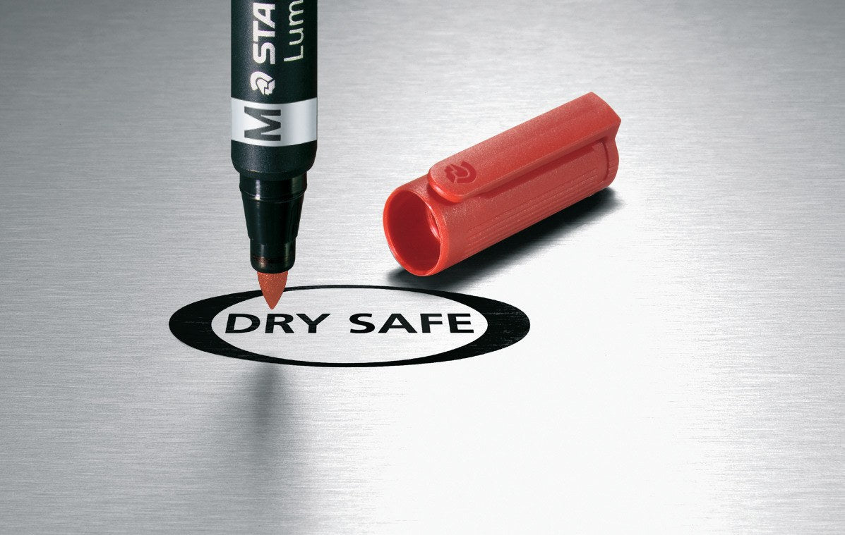 Red Lumocolor duo marker standing uncapped on brushed metal above a DRY SAFE logo, red cap beside it