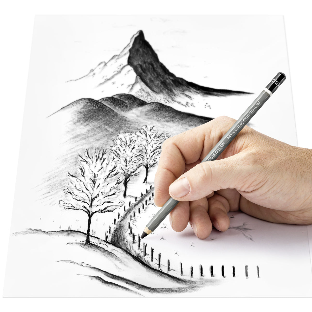 Hand drawing a mountain, bare trees and a fenced path in charcoal with a Staedtler Mars Lumograph charcoal pencil, Staedtler range photo