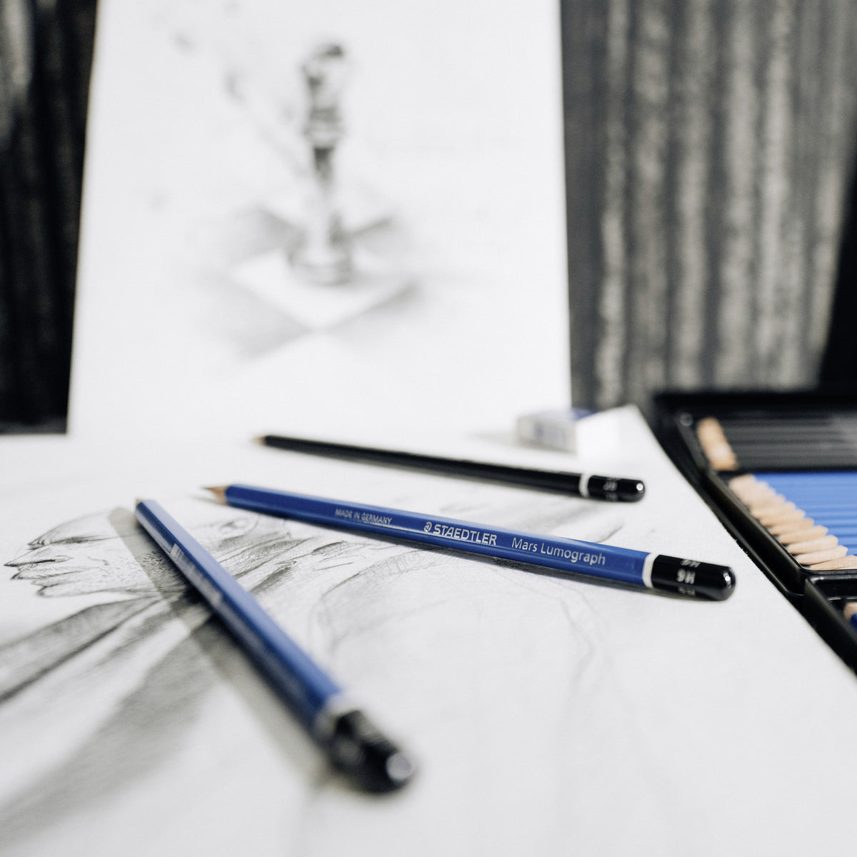 Blue Mars Lumograph pencils resting on a pencil drawing of a chess piece on a desk